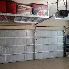 A garage with two doors and a ceiling rack above it.