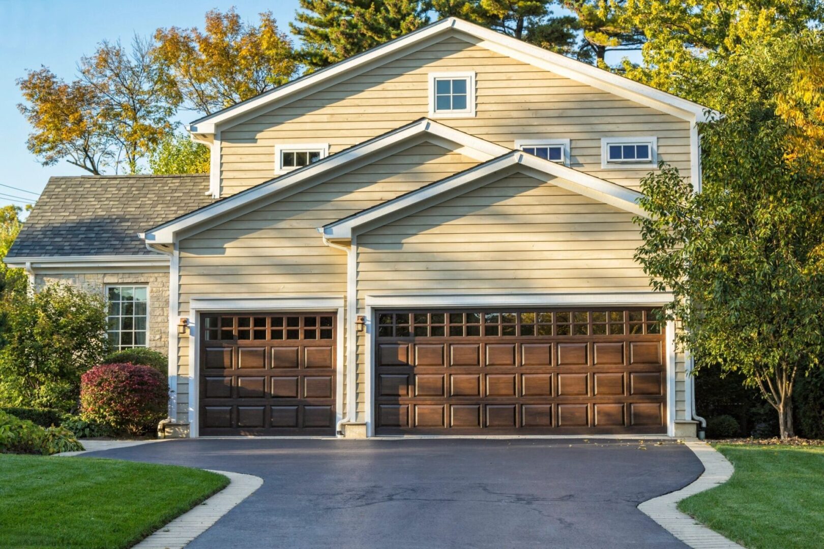 A couple of brown garage doors in front of a house.